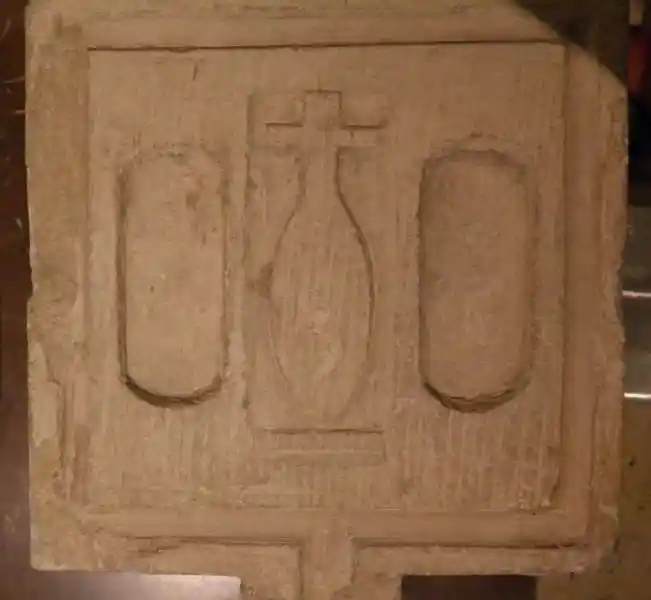 An altar with a symbol of Nefer, a cross on top of an elongated circle, in the middle of two holes